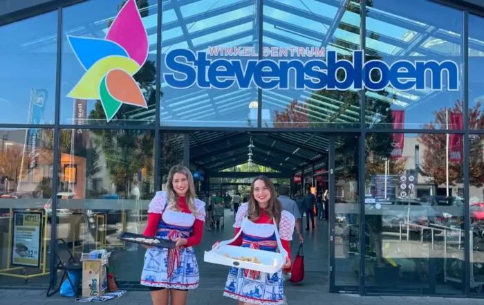 two women in matching outfits posing for a picture in front of a glass building